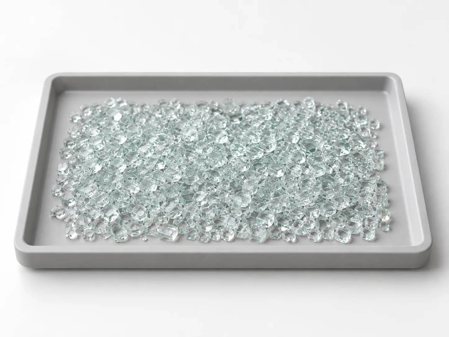 Small tempered-glass sample broken into many small fragments on a shallow tray.